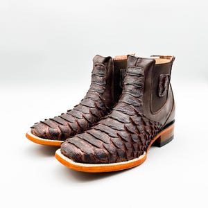 May include: A pair of brown leather ankle boots with a snakeskin pattern. The boots have a pointed toe and a low heel.
