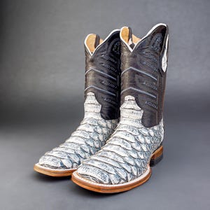 May include: A pair of white and black cowboy boots with a snakeskin pattern. The boots have a pointed toe and a high heel.