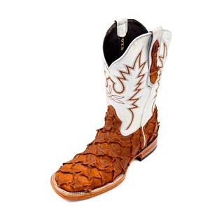 May include: A single cowboy boot with a square toe. The boot features a white shaft with brown stitching and a brown, textured vamp. The boot is made of leather and has a stacked heel.