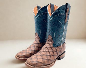 May include: A pair of cowboy boots with a brown, diamond-patterned foot and a dark blue leather upper. The boots have a white stitch design and a square toe. The interior is tan.
