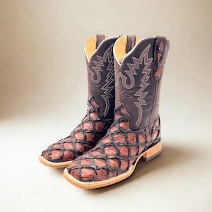 May include: A pair of brown leather cowboy boots with a square toe. The boots have a unique fish scale pattern on the foot and a decorative stitched design on the shaft. The boots are approximately 12 inches tall.