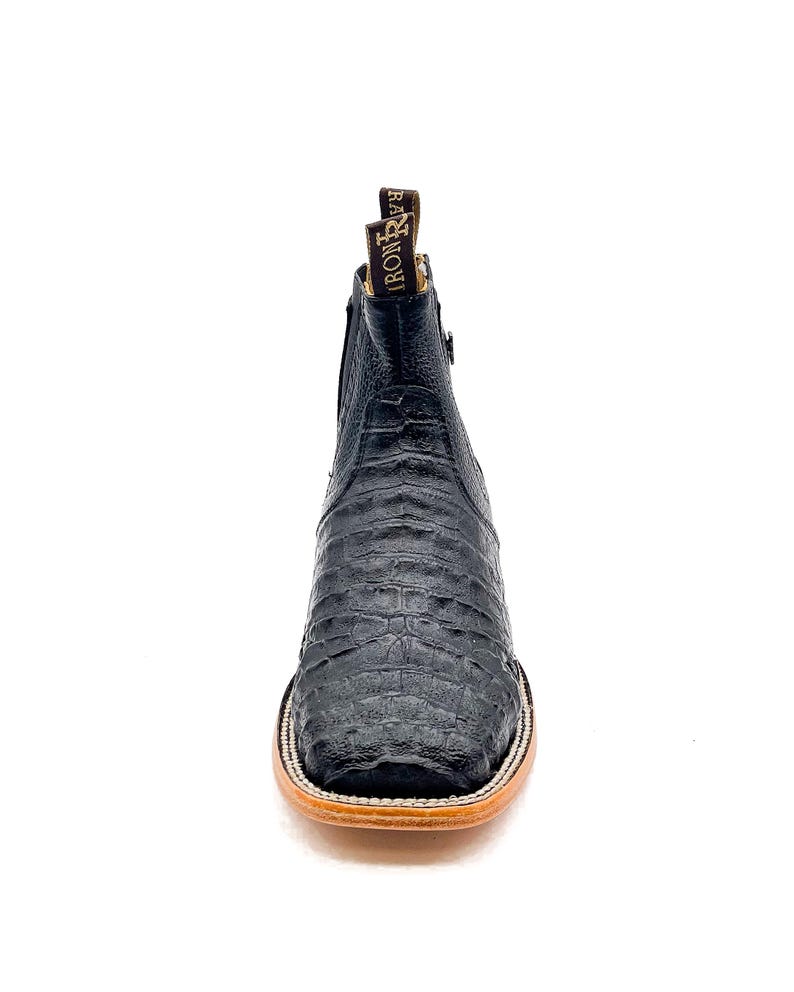 May include: Black leather ankle boot with a square toe and a textured, crocodile-like pattern. The boot has a zipper on the side and a brown sole. The brand name "IRON RIVER" is visible on the pull tab.