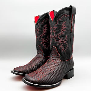 May include: A pair of black cowboy boots with red stitching and a snakeskin pattern. The boots have a pointed toe and a low heel.
