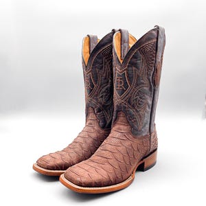 May include: A pair of brown leather cowboy boots with intricate stitching and a decorative design on the shaft. The boots have a pointed toe and a stacked heel.