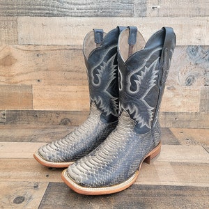 May include: A pair of black cowboy boots with a snakeskin pattern. The boots have a pointed toe and a low heel.