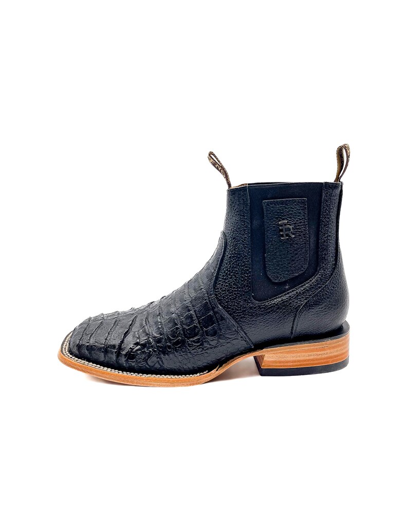 May include: Black leather ankle boots with a square toe and a textured, crocodile-like pattern. The boots have a pull tab and a light brown sole. The heel is approximately 1 inch high.