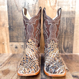 Puede incluir: Un par de botas de vaquero de cuero marr&oacute;n. El pie presenta un dise&ntilde;o tejido, mientras que la ca&ntilde;a superior tiene un patr&oacute;n cosido decorativo. Las botas tienen una puntera cuadrada y una suela marr&oacute;n claro.