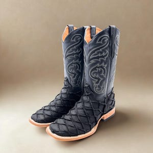 May include: A pair of black cowboy boots with a unique diamond-patterned texture on the foot and lower leg. The boots have decorative stitching and a square toe. The interior is a light tan color.