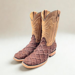 May include: A pair of brown cowboy boots with a unique scale-like pattern on the foot and a tan leather upper. The boots have a square toe and a stacked heel, showcasing a classic Western design.