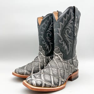 May include: A pair of black cowboy boots with a white patterned design. The boots have a pointed toe and a brown leather sole.
