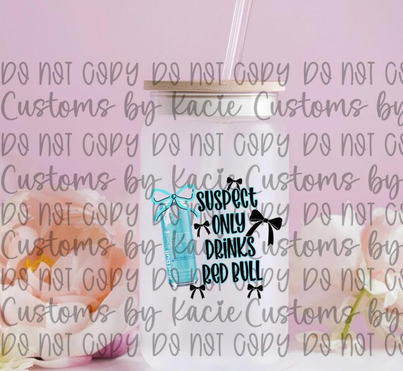 May include: A clear glass tumbler with a bamboo lid and a straw. The tumbler features a Red Bull can graphic and the text "Suspect Only Drinks Red Bull" with bow accents. The background is a soft pink.
