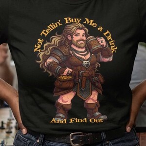May include: A black short-sleeve t-shirt featuring a graphic of a bearded fantasy character holding a wooden mug. The text "Not Tellin' Buy Me a Drink And Find Out" is printed in a circular yellow font around the central character illustration.