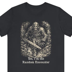 May include: Black t-shirt featuring a detailed illustration of a skeletal knight in armor, holding a sword. The knight is set against a dungeon backdrop. The text "Yes, I'm the Random Encounter" is printed below the image.