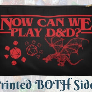 May include: Black zippered pouch with red text that reads "NOW CAN WE PLAY D&D?" along with dice and a dragon graphic. The bottom of the pouch reads "Printed BOTH Sides".
