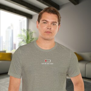 Op de afbeelding: Een heidegrijs T-shirt met een witte afbeelding van een bijna lege batterij en de tekst "Social Battery".