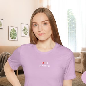 Op de afbeelding: Een lila t-shirt met een witte afbeelding van een bijna lege batterij en de tekst "Social Battery".