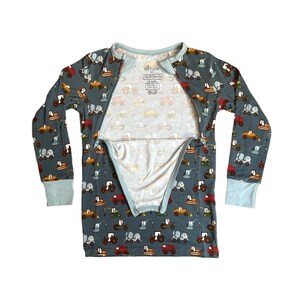 Puede incluir: Un conjunto de pijama de manga larga en color verde azulado apagado, estampado con varios veh&iacute;culos de construcci&oacute;n en tonos amarillos, naranjas, rojos y grises. Los pu&ntilde;os y el cuello son de color azul claro. El pijama tiene una cremallera completa.