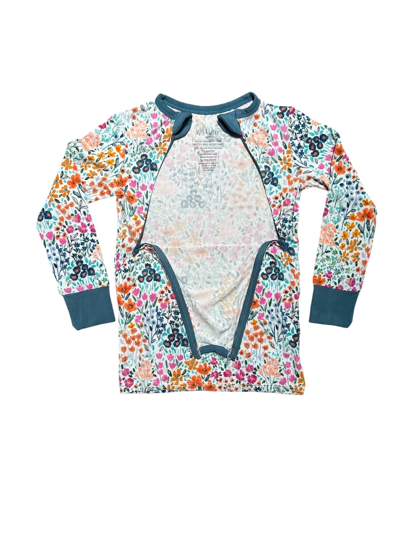 K&ouml;nnte beinhalten: Ein Schlafanzug-Set mit floralem Print und langen &Auml;rmeln mit t&uuml;rkisfarbenem Besatz. Der Schlafanzug hat ein farbenfrohes Muster aus Blumen in Orange-, Rosa- und Blaut&ouml;nen auf wei&szlig;em Hintergrund. Das Set hat einen Rei&szlig;verschluss vorne.