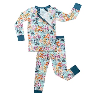 K&ouml;nnte beinhalten: Pyjama-Set mit floralem Muster und tealfarbenem Rei&szlig;verschluss, B&uuml;ndchen und Ausschnitt. Das lang&auml;rmlige Oberteil und die Hose zeigen ein farbenfrohes Blumenmuster in Rosa, Orange und Blau auf hellem Hintergrund.