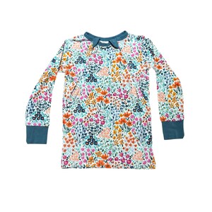 K&ouml;nnte beinhalten: Ein lang&auml;rmliges Shirt mit floralem Muster. Das Shirt hat einen wei&szlig;en Hintergrund mit einem farbenfrohen Blumendesign in Orange-, Rosa-, Blau- und Gr&uuml;nt&ouml;nen. Der Kragen und die Manschetten sind einfarbig t&uuml;rkis. Das Shirt ist aus einem weichen, bequemen Material.