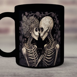 May include: Black coffee mug with a graphic of two skeletons embracing, surrounded by roses. The skeletons are wearing floral crowns and are looking at each other.
