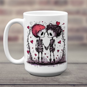 May include: White ceramic coffee mug with a graphic of two skeletons holding hands. The skeletons are wearing red hearts and are surrounded by a heart-shaped frame. The mug is 15 ounces.