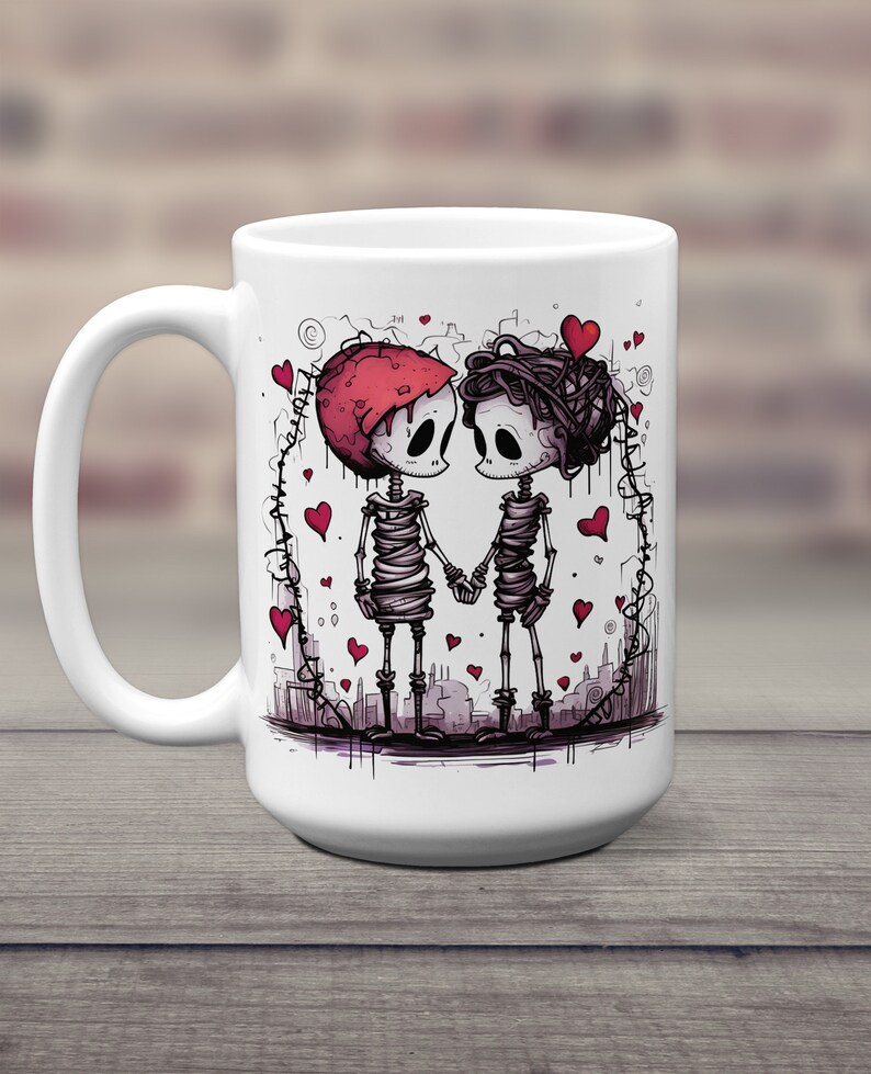 May include: White ceramic coffee mug with a graphic of two skeletons holding hands. The skeletons are wearing red hearts and are surrounded by a heart-shaped frame. The mug is 15 ounces.