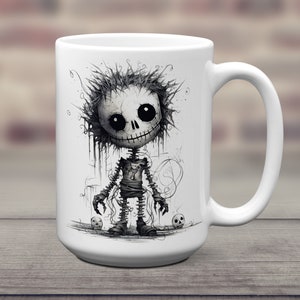 May include: White ceramic coffee mug with a black and white illustration of a cartoon skeleton with a mischievous grin. The skeleton is wearing tattered clothing and has a skull in each hand.