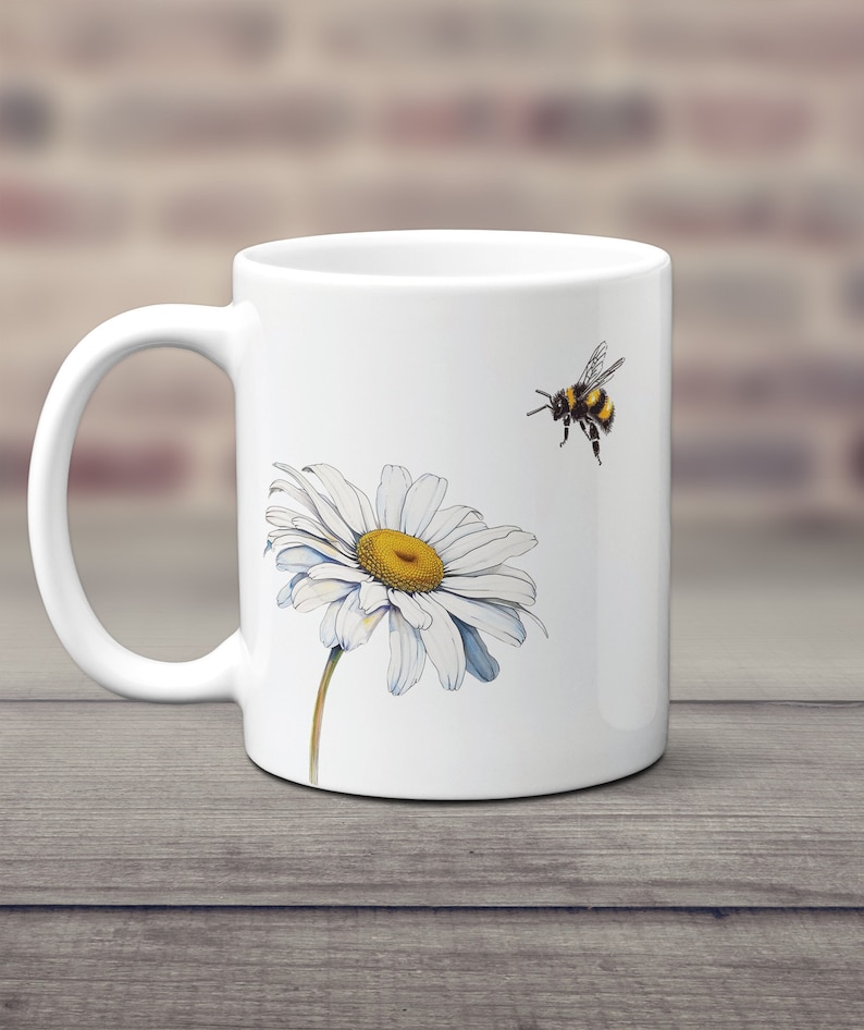 May include: White ceramic mug with a white daisy and a black and yellow bumblebee on a white background.