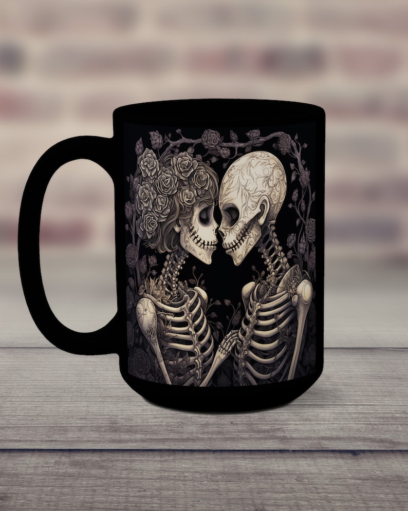 May include: Black coffee mug with a graphic of two skeletons embracing, surrounded by roses. The skeletons are wearing floral crowns and have intricate details.