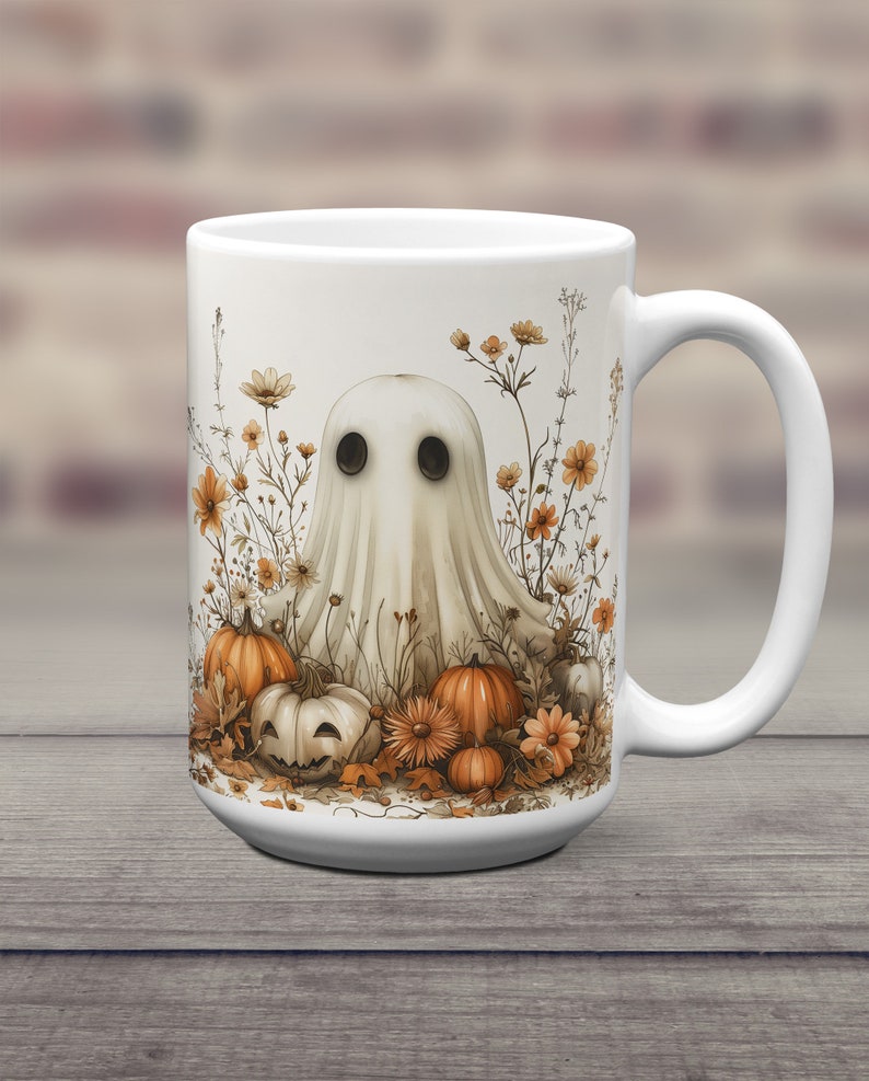 K&ouml;nnte beinhalten: Eine wei&szlig;e Keramiktasse mit einer Geisterillustration, umgeben von K&uuml;rbissen und Blumen. Der Geist ist wei&szlig; mit schwarzen Augen und einem schwachen L&auml;cheln. Die K&uuml;rbisse sind orange und braun, einige sind zu Jack-o'-Lanterns geschnitzt. Die Blumen sind gelb und orange.