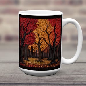 K&ouml;nnte beinhalten: Wei&szlig;e Keramiktasse mit einer farbenfrohen Illustration einer Waldszene. Die B&auml;ume sind stilisiert und haben rote, orange und gelbe Bl&auml;tter. Der Hintergrund ist schwarz und es liegen Bl&auml;tter auf dem Boden.