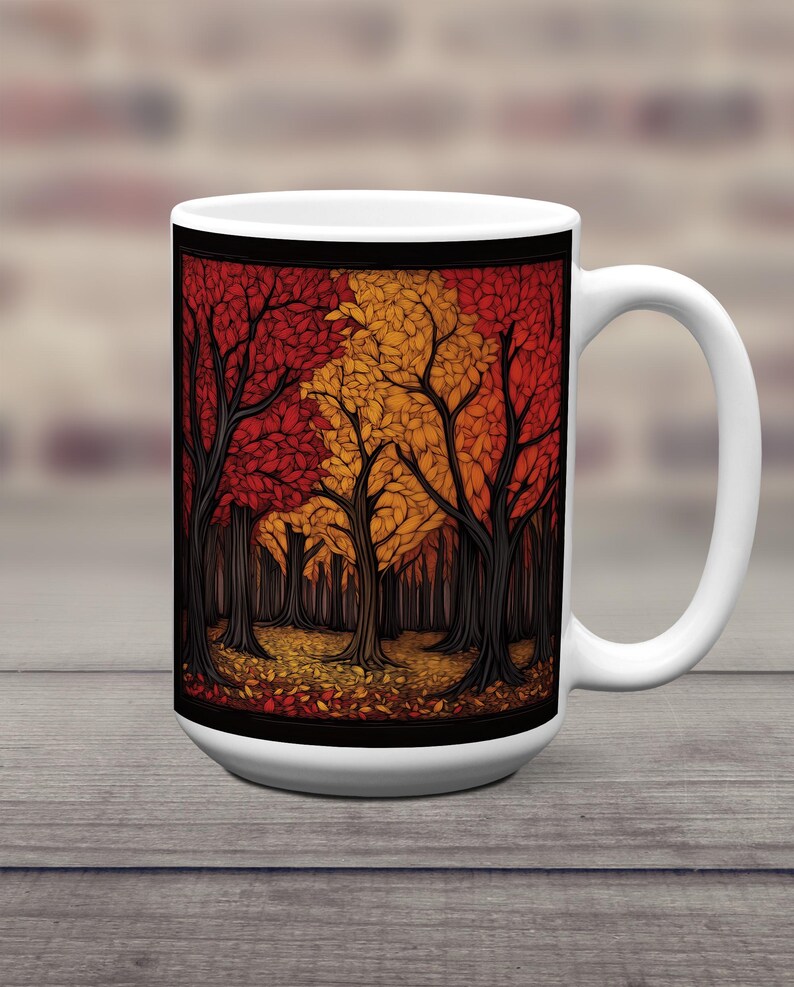 K&ouml;nnte beinhalten: Wei&szlig;e Keramiktasse mit einer farbenfrohen Illustration einer Waldszene. Die B&auml;ume sind stilisiert und haben rote, orange und gelbe Bl&auml;tter. Der Hintergrund ist schwarz und es liegen Bl&auml;tter auf dem Boden.