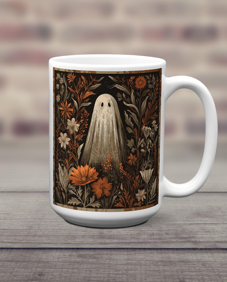 May include: White ceramic mug with a vintage illustration of a ghost in a floral garden. The design features orange, brown, and white flowers against a black background. The mug has a large handle and a glossy finish.