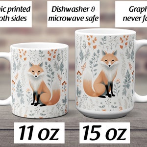 May include: Two white ceramic mugs with a fox graphic printed on both sides. The mugs have a floral pattern with orange, gray, and green colors. The mug on the left is 11 oz and the mug on the right is 15 oz.  "Graphic printed on both sides", "Dishwasher & microwave safe", and "Graphic never fades" are written on the top of the image.
