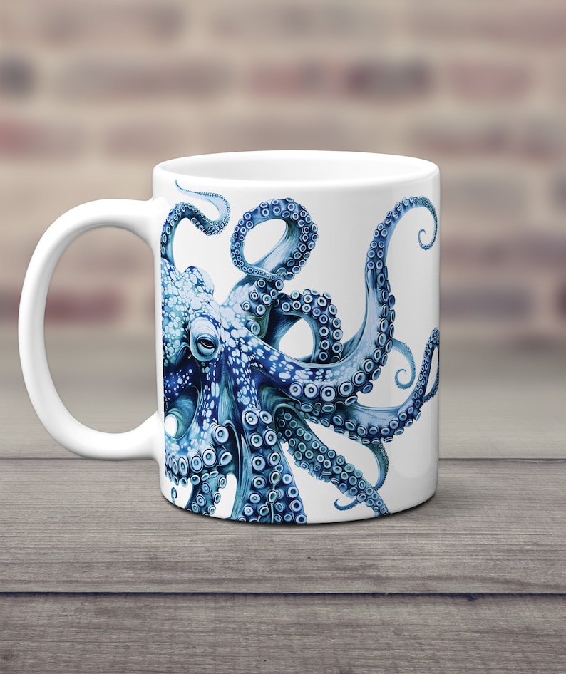 May include: A white ceramic mug featuring a detailed illustration of a blue octopus. The octopus has multiple tentacles with visible suction cups, rendered in various shades of blue and white, wrapping around the side of the cylindrical mug.