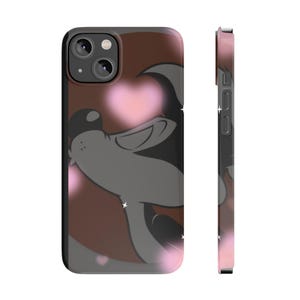 Puede incluir: Funda de teléfono negra con un diseño de lobo de dibujos animados sobre un fondo marrón y acentos de corazón rosa. La funda tiene un acabado brillante y un borde negro, con un degradado rosa en el lateral.