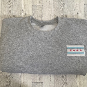 May include: A gray sweatshirt with a white and blue Chicago flag patch on the left side.