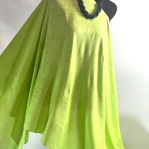 May include: A bright green fabric with a subtle embossed pattern. The fabric is draped over a mannequin.