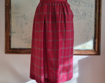 May include: A red and white plaid skirt with a high waist and a gathered front. The skirt is midi length and has a simple, classic design.