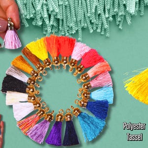 May include: A collection of colorful polyester tassels in various shades, including pink, yellow, orange, and blue, arranged in a circular pattern. Each tassel has a gold-colored cap. The image also shows a few tassels held in a hand.