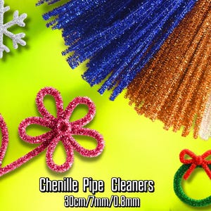 Peut inclure: Assortiment de cure-pipes chenille colorés en bleu, orange et blanc, avec une fleur rouge, une couronne verte avec un nœud rouge et un flocon de neige argenté. Le texte "Chenille Pipe Cleaners 30cm/7mm/0.8mm" est également visible.