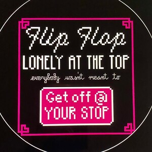 以下が含まれることがあります： ピンクと白の看板に「Flip Flop LONELY AT THE TOP everybody wasn't meant to Get off @ YOUR STOP」というテキストが書かれています。