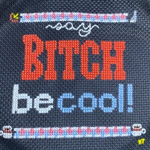 Può includere: Un ricamo a punto croce in bianco e nero con il testo "Say Bitch be cool!" in filo rosso, bianco e blu.