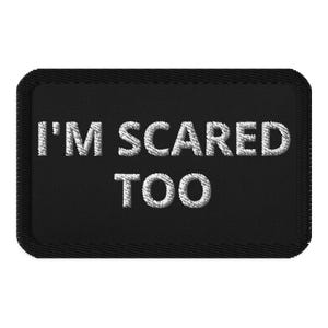 Könnte beinhalten: Schwarzer rechteckiger Aufnäher mit dem gestickten Text "I'M SCARED TOO" in Weiß. Der Aufnäher hat einen schwarzen Rand und ist zum Aufnähen oder Aufbügeln auf Kleidung oder Accessoires gedacht. Der Text ist in einer fetten, serifenlosen Schrift.