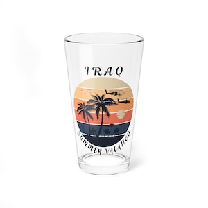 May include: A clear glass with a graphic of palm trees, a sunset, and helicopters with the text "IRAQ Summer Vacation" printed on it.