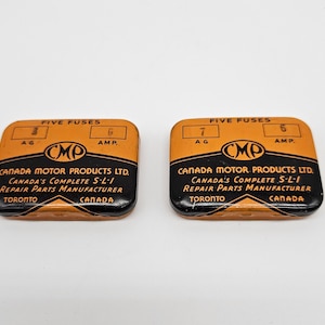 Puede incluir: Dos cajas de metal naranja y negro con el texto "FIVE FUSES" y "CMP" en ellas. Las cajas contienen cinco fusibles cada una, con un fusible de 7 amperios y un fusible de 6 amperios visibles.