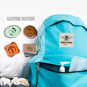 May include: Leather patches with initials and a bee logo on a blue backpack. The patches are in various colors and shapes, including round, oval, and square. The backpack has a zippered pocket with a face mask and hand sanitizer inside.