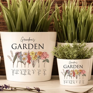 May include: Four white ceramic flower pots with the text "Grandma's Garden" and a floral design. The pots are arranged in a row from largest to smallest. The largest pot has the names of different flowers written below the floral design.