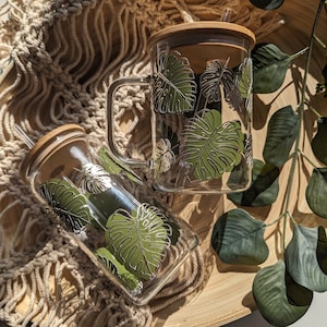 Olivgrüner und champagner-goldener Monstera Blatt Glasbecher oder Glasbecher mit Bambusdeckel & wiederverwendbarem Plastik-Trinkhalm. Kaffee Tasse. Eiskaffee.